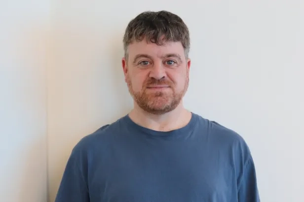 Adult male in smart casual attire smiling.