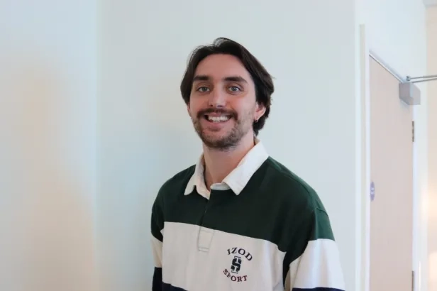 Young male in business casual smiling.