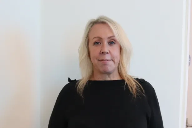 Middle aged woman in business casual smiling.