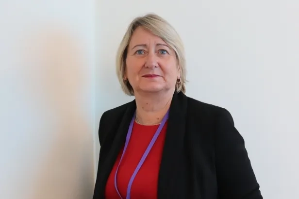 Older woman in a professional attire smiling.